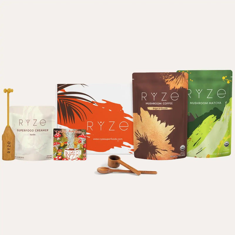 Collection of RYZE products including Mushroom Coffee, Mushoom Matcha, Superfood Creamer, a magnet, a wooden frother and wooden spoons on a white background